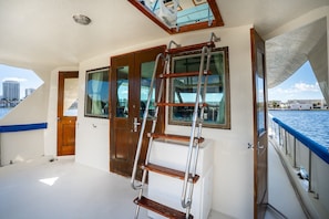 A boat interior with a wooden ladder, windows, and a door.