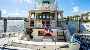 A boat docked at a marina with a view of a cityscape in the background. - Stay Aboard a Vintage Hatteras 53' Motor Yacht in Aventura-A Unique Experience! (Aventura)