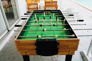 Ein Kicker mit Holzrahmen und grüner Spielfläche.