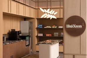 A modern kitchen with wooden cabinets, a built-in refrigerator, a coffee machine, and a central island with a marble countertop. - Hilton Garden Inn Chengdu Jinnan Tianjie (Chengdu)