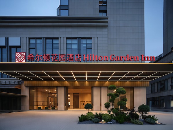 A hotel entrance with a modern facade, a prominent sign, and a landscaped garden area. - Hilton Garden Inn Chengdu Jinnan Tianjie (Chengdu)