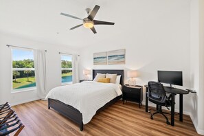 Ein Schlafzimmer mit einem Bett, einem Schreibtisch, einem Stuhl und einem Deckenventilator.
