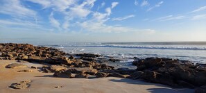Ein felsiger Strand mit Wellen, blauem Himmel und keinerlei Bebauung oder Annehmlichkeiten.