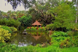 Ein friedlicher Garten mit einem Pavillon, Teich und üppiger Vegetation.