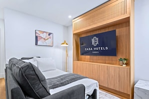 Moderni hotellihuone, jossa on sänky, työpöytä, lamppu ja seinälle kiinnitetty kyltti, jossa lukee Casa Hotels Toronto.