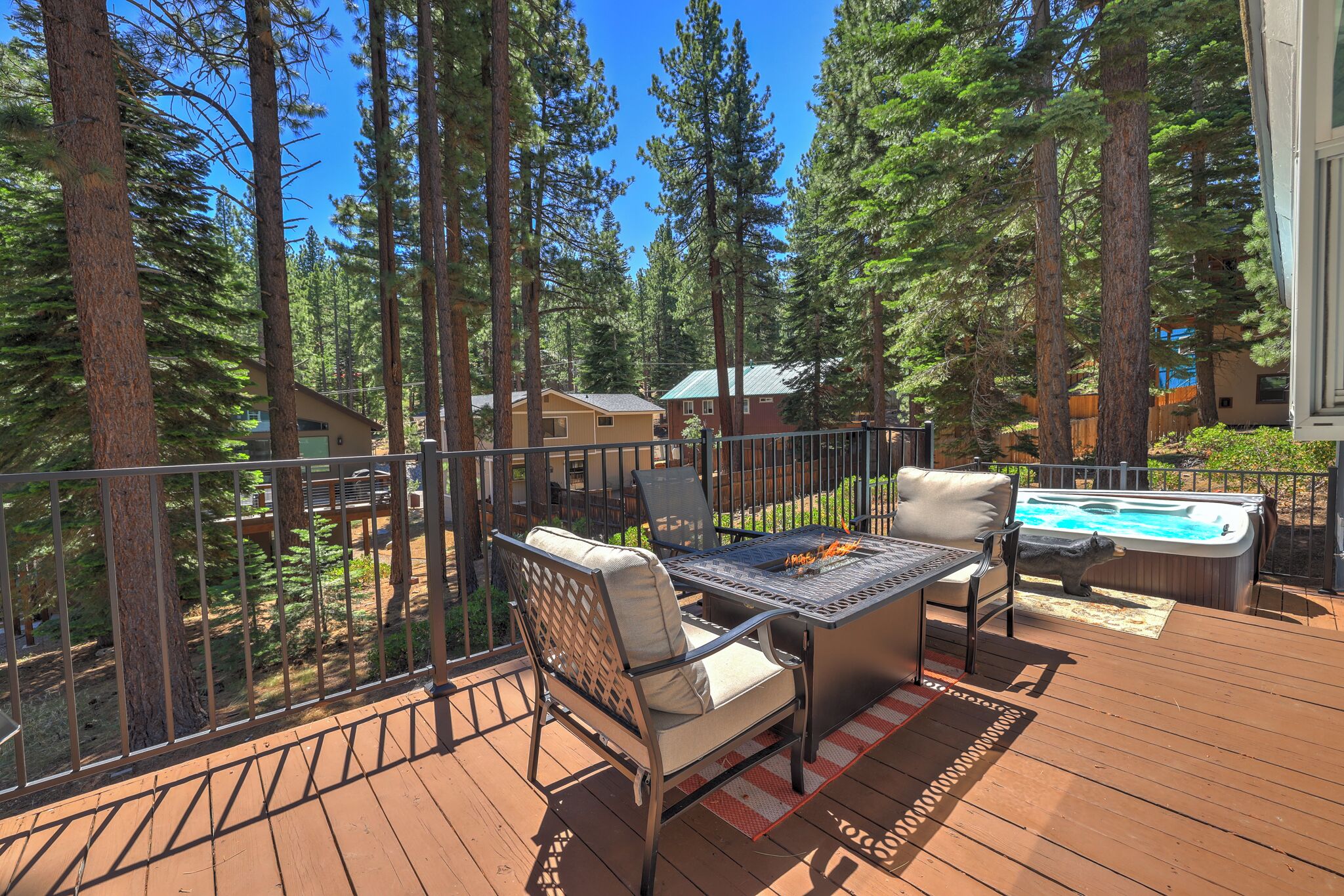 Une terrasse dotée de mobilier d’extérieur, d’un jacuzzi et offrant une vue sur une zone boisée.