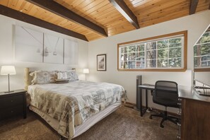 Een slaapkamer met een bed, nachtkastjes, een bureau en een stoel.
