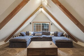 Slaapkamer in loftstijl met een grote hoekbank, een houten salontafel en een raam met zonwering.