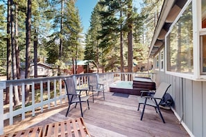 Eine Holzterrasse mit Sitzgelegenheiten, umgeben von hohen Bäumen.