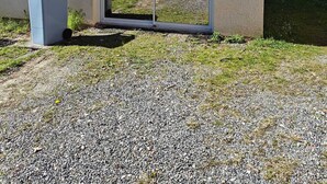 A building with a garage door, a trash bin, and a gravel driveway. - Apartment near Dune du Pilat (La Teste-de-Buch)