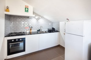 Eine Küche mit weißen Schränken, einer schwarzen Arbeitsplatte, einem Herd, einem Backofen und einem Kühlschrank.