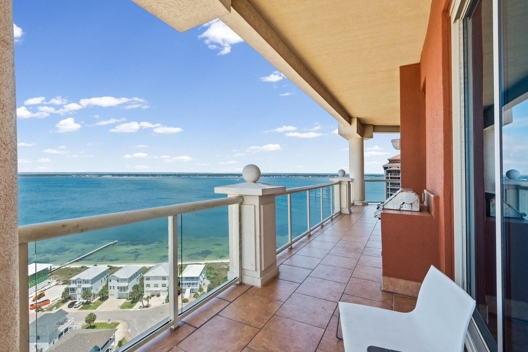 A balcony with a view of the ocean and a residential area.