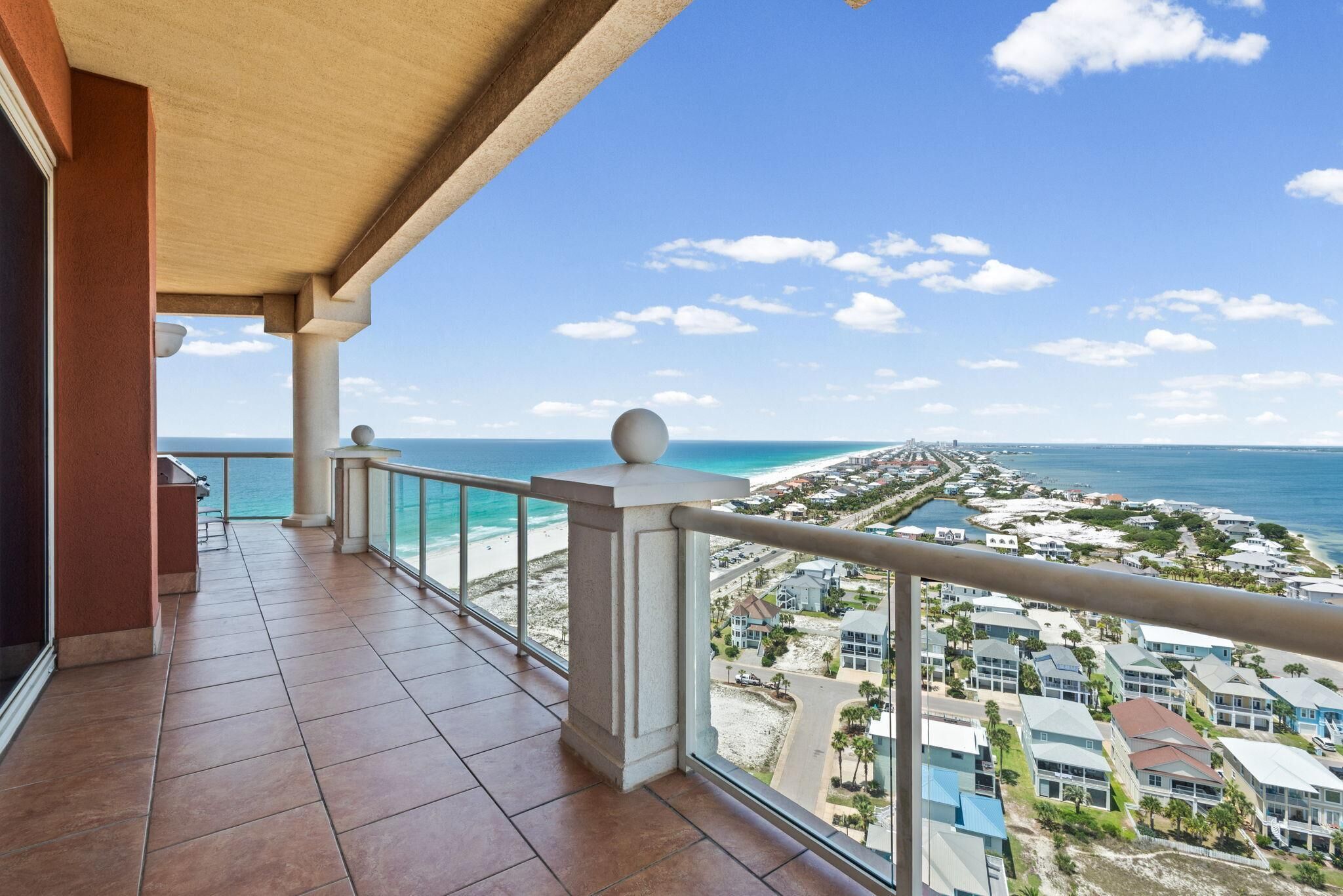 A balcony with a view of the ocean and a resort area.