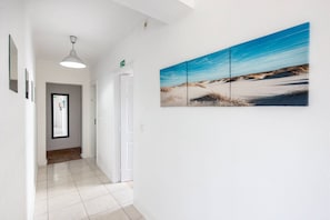 Ein Flur mit weißer Wand, einem gerahmten Bild und einer Tür.