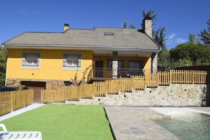 Une maison jaune avec un toit en tuiles, des murs en pierre, une clôture en bois, un chemin en pierre et une piscine.