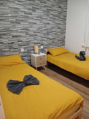 Een kamer met twee bedden, een nachtkastje, een lamp en een wand met een patroon.