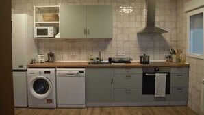 A compact kitchen with a washing machine, microwave, and a sink.