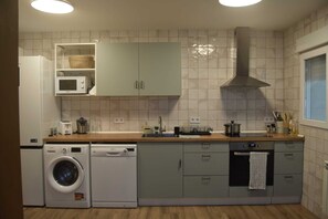 Een kleine keuken met een wasmachine, magnetron en spoelbak.