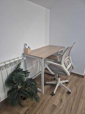 Un espace de travail avec un bureau blanc, un fauteuil de bureau moderne et une plante en pot.
