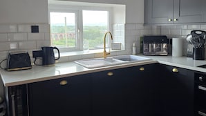 A modern kitchen with a window, dark cabinetry, and a coffee maker.