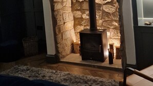 A living room with a stone fireplace, a blue sofa, and a modern art piece above the fireplace.