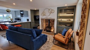 A modern kitchen with grey cabinets, a central island, and a dining area with red chairs.