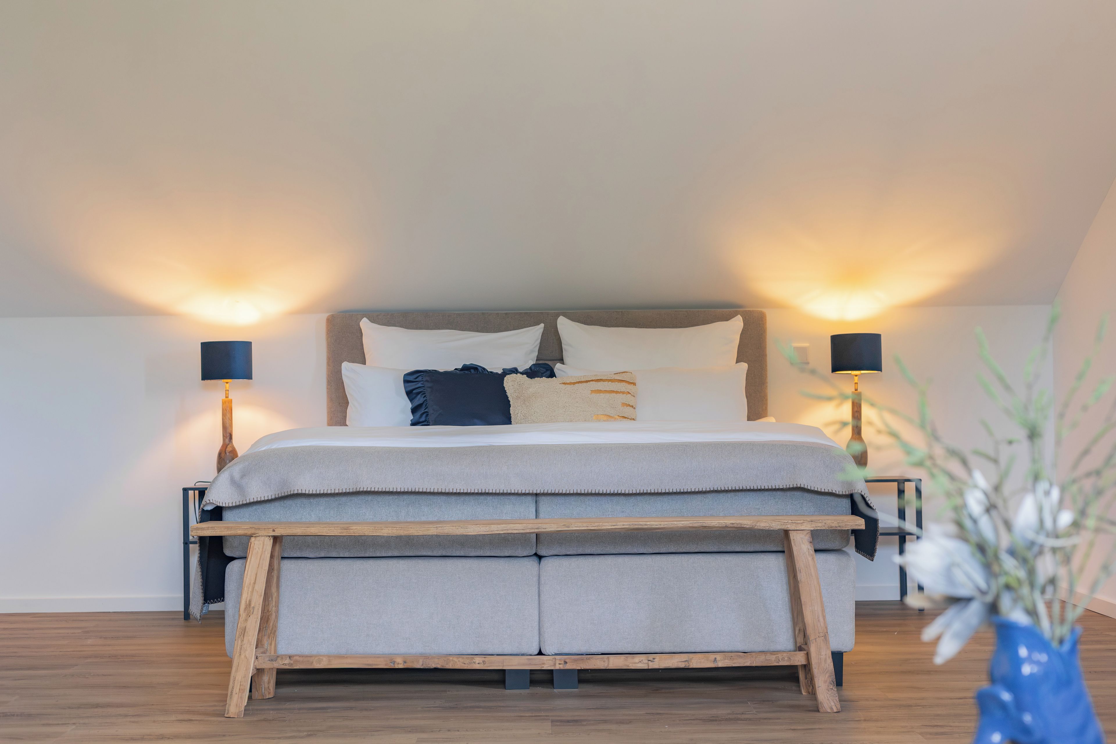 Una camera da letto con un letto, comodini, lampade e una pianta.