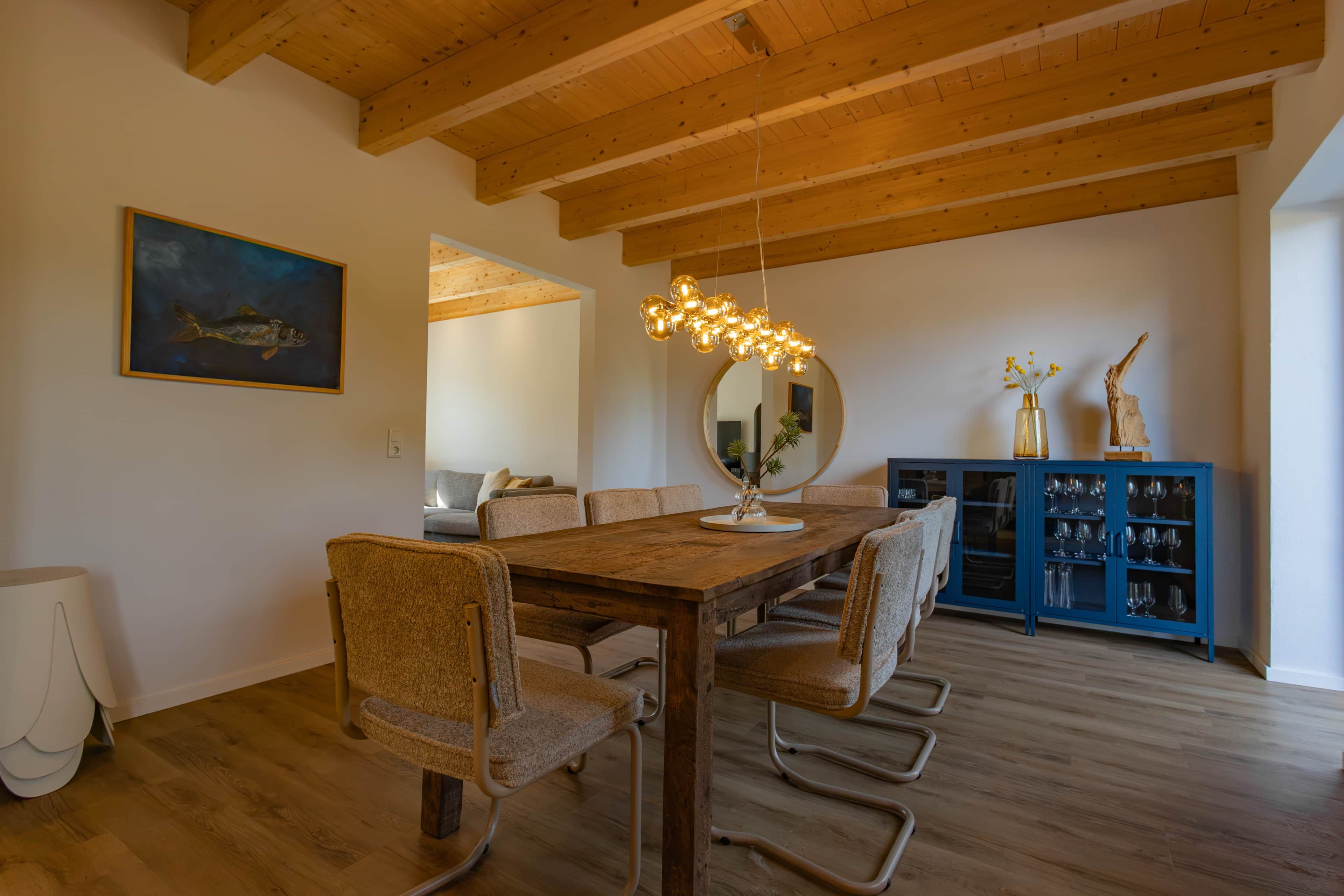 A dining area with a wooden table, chairs, and a hanging light fixture.