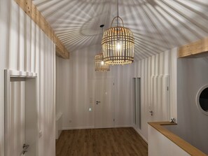 En hall med ett träpanelat tak, en hängande lampa och en dörr längst ner.