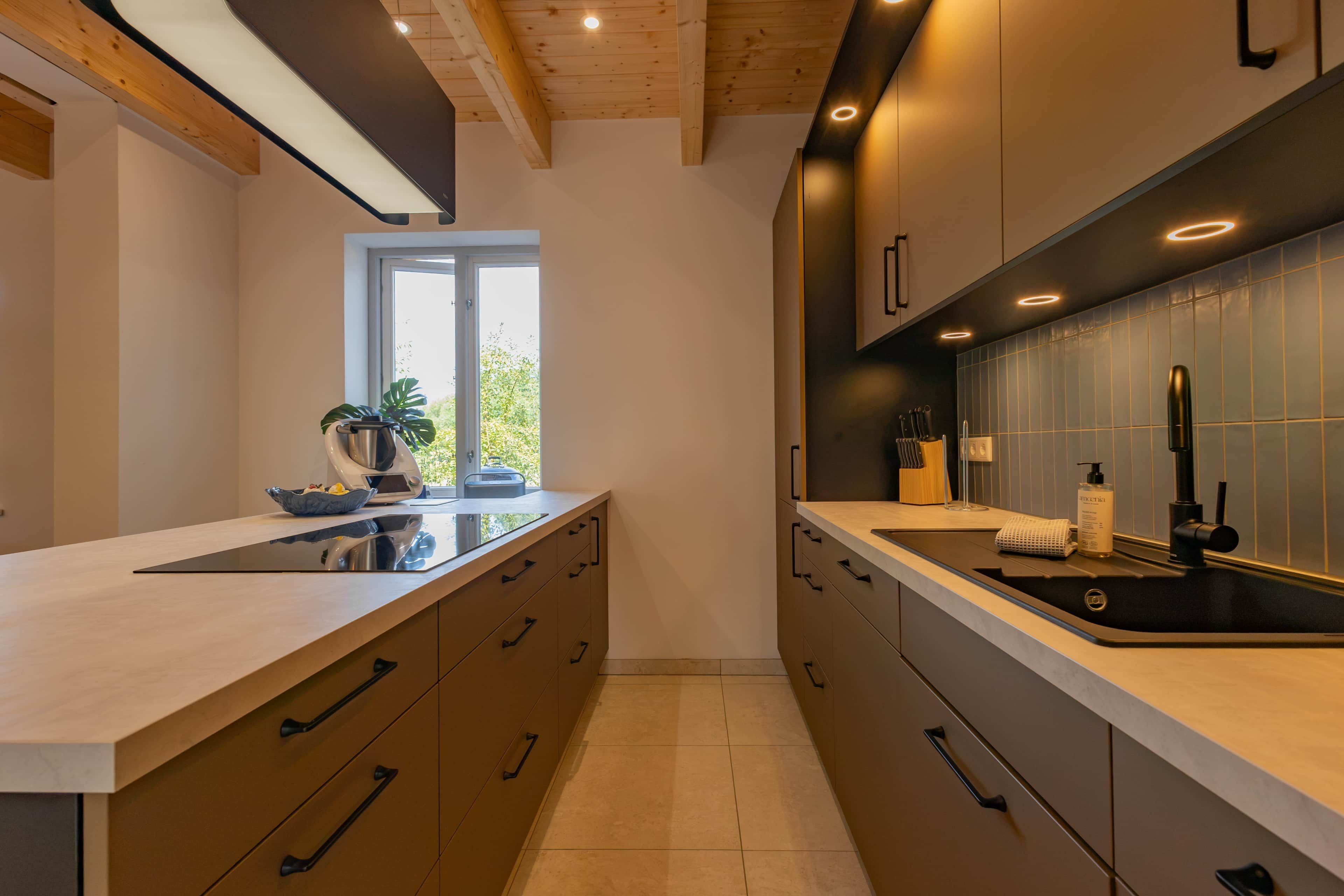 Une cuisine moderne dotée d’une grande fenêtre, de meubles en bois et d’un évier en acier inoxydable.