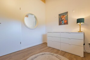 Ein Zimmer mit einem weißen Schminktisch, einem runden Spiegel, einem Gemälde eines Stiers und einer Lampe.