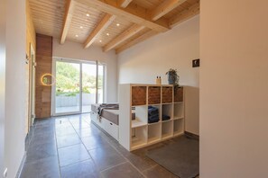Ein Flur mit Holzboden, einer Schiebetür zu einem Außenbereich und einer Einbauschränken mit gefalteter Kleidung.