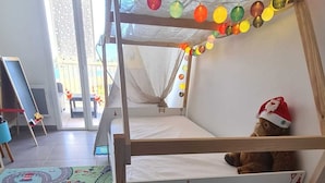 Un lit superposé pour enfant avec un matelas aux motifs de chantier de construction, un ours en peluche et des lumières colorées.