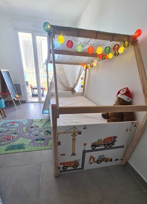 Ein Kinderstockbett mit einem thematisch passenden Matratzenbezug zum Baugerüst-Motiv, einem Teddybären und bunten Lichterketten.