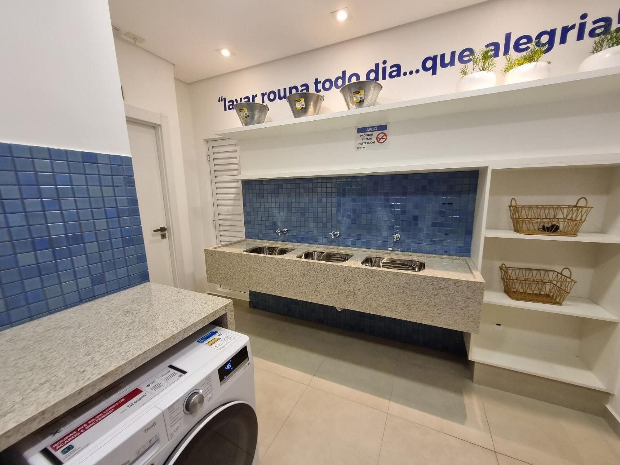 Een wasserette met een wasmachine, meerdere spoelbakken en een blauwe betegelde spatwand.