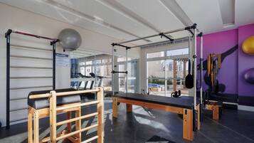 A gym with exercise equipment, a Pilates area, and large windows.