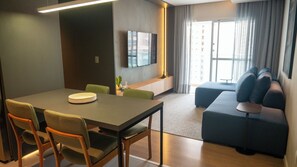 Une chambre d’hôtel moderne dotée d’un coin repas, d’un canapé et d’un téléviseur fixé au mur.