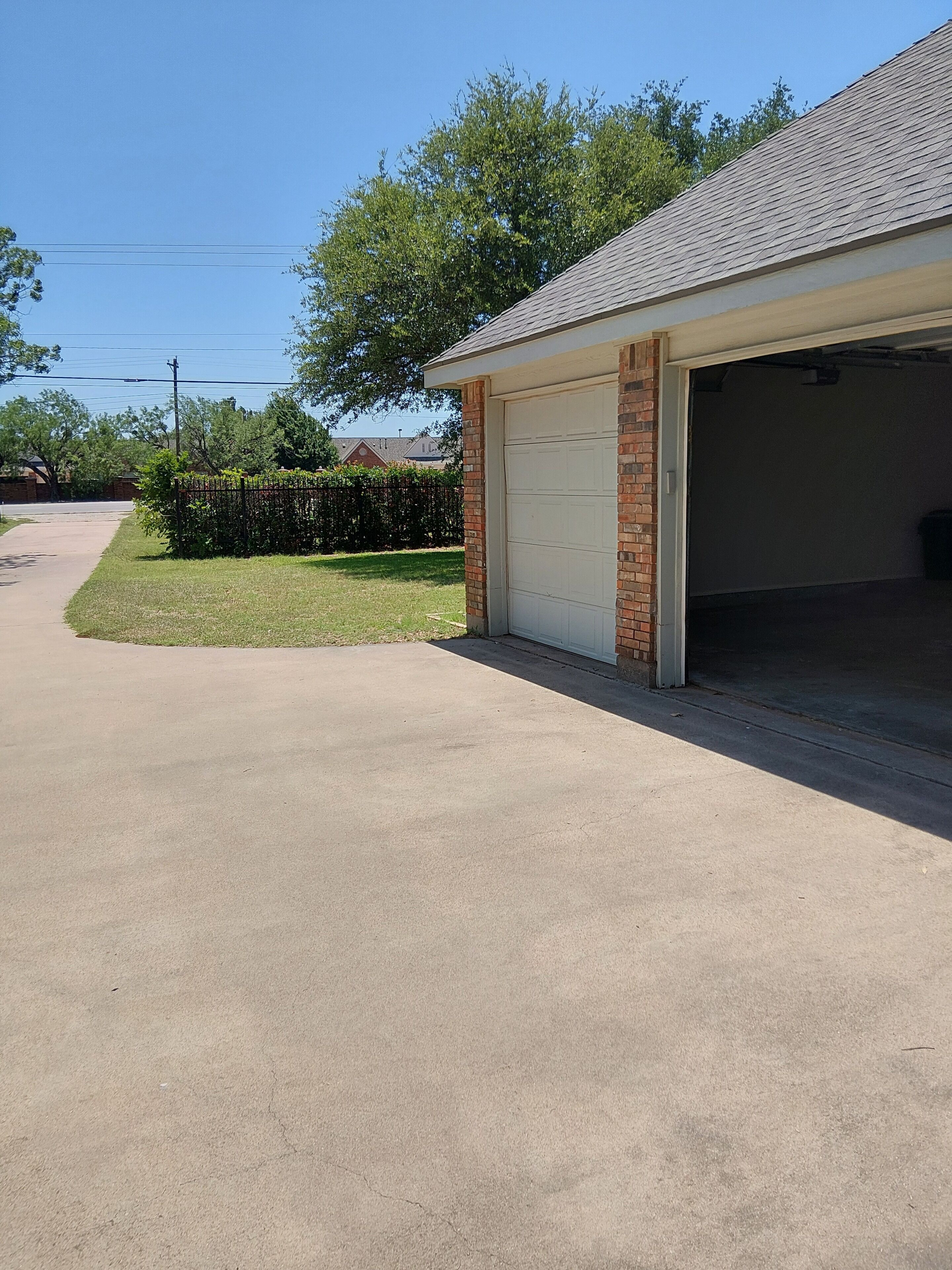 Un garage résidentiel avec une façade en briques et une porte de garage blanche.