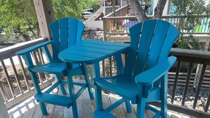 A wooden deck with a table and four blue Adirondack chairs. - Lily's Pad (Kill Devil Hills)