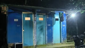 Uma fileira de portas azuis com os números 2000, 2000 e 2000, uma motocicleta estacionada à direita e uma pequena construção com telhado de metal.