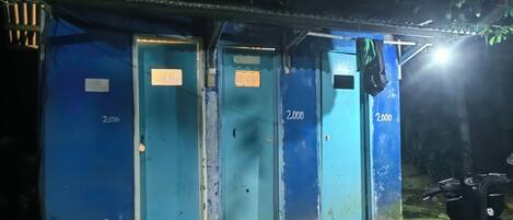 A row of blue doors with numbers 2000, 2000, and 2000, a motorcycle parked to the right, and a small structure with a metal roof.