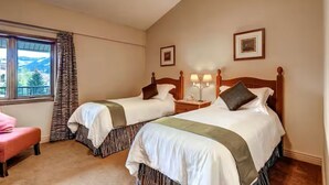 Een hotelkamer met twee bedden, een raam met uitzicht en een stoel.