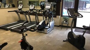 Een sportschool met loopbanden, een elliptische trainer en een hometrainer.