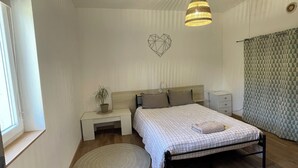 Una camera da letto con un letto, comodini, un lampadario a sospensione, un decoro a parete e una finestra.