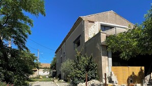 Un edificio a due piani con facciata in pietra, un cancello in legno e un vialetto lastricato.