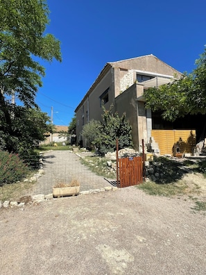 Un bùtiment à deux étages avec une façade en pierre, une porte en bois et une allée pavée.