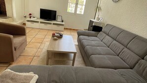 Un soggiorno con divano, tavolino, televisione e una finestra vista.