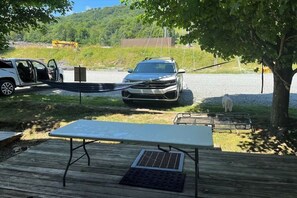 Ein Fahrzeug auf einer Schotterfläche, in der Nähe ein Picknicktisch und ein Grill.