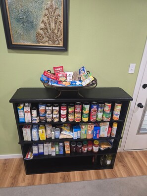 A pantry stocked with various food items and a decorative tray on top. - Infinity Guest House - Corporate Housing (Sterlington)