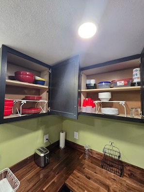 A kitchen with wooden cabinets, a toaster, a kettle, and various kitchenware.